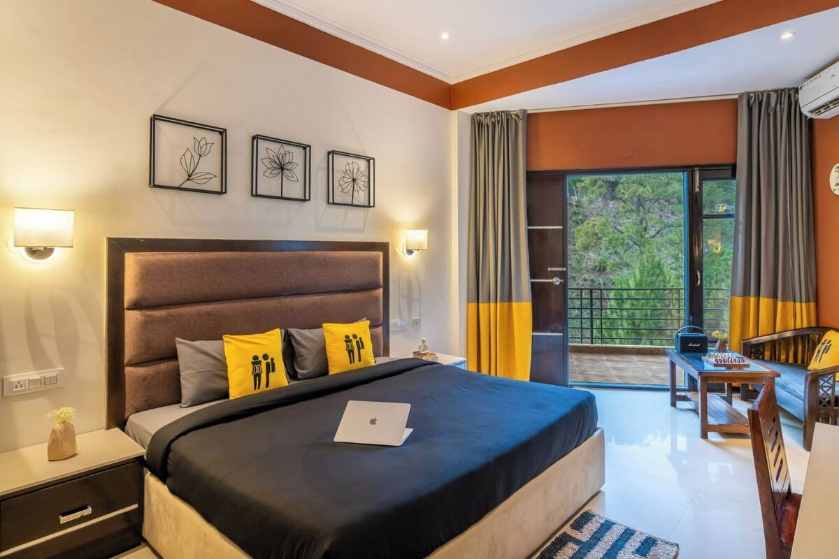 Une chambre avec un grand lit, des lampes de chevet, une table de chevet, un ordinateur portable posé sur le lit et une vue sur l’extérieur grâce à une porte coulissante.