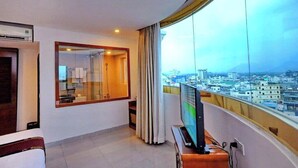 A hotel room with a large window, a television, and a view of a cityscape.