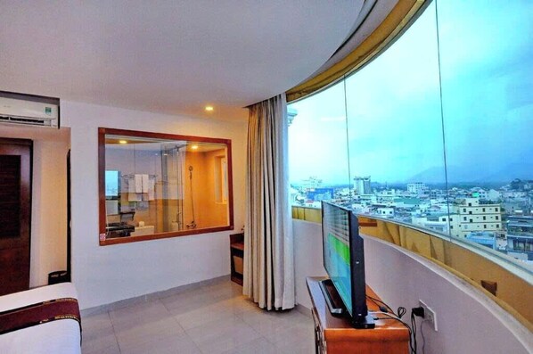 A hotel room with a large window, a television, and a view of a cityscape. - Sunniva Hotel Nha Trang (Nha Trang)