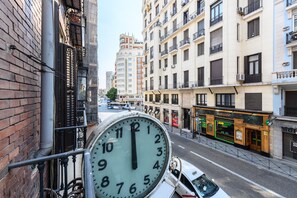 A street view with a large clock, a Subway restaurant, and a building with a clock tower in the background.