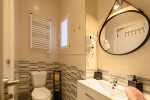 A bathroom with a toilet, a sink, a mirror, and a towel rack.