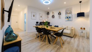 Un espace repas moderne avec une table en bois, des chaises noires, un canapé blanc et un luminaire suspendu au plafond.