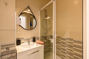 Un baño con lavamanos, espejo y ducha.