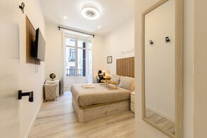 A modern bedroom with a bed, bedside table, and a TV mounted on the wall. - Washington: room with comfort and shared areas Gran Vía-Madrid (Madrid)