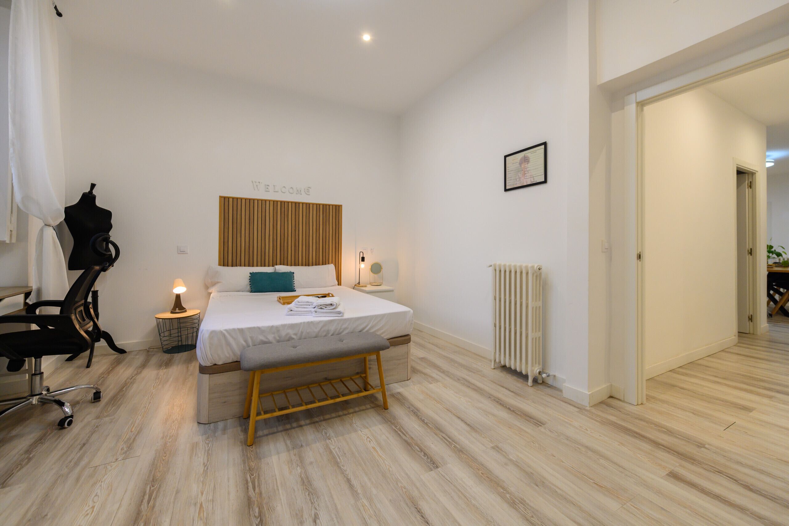 Une chambre à coucher moderne avec un lit, une table de chevet, une lampe et un mannequin.