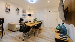 Una sala de reuniones moderna con una mesa de madera, sillas negras, un sofá y un televisor montado en la pared.