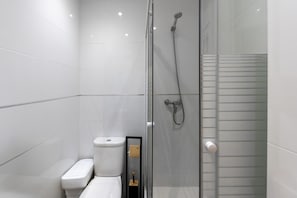 Une salle de bain moderne dotée d’une douche à parois de verre, de toilettes et d’un bidet.