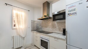 Une cuisine compacte avec un crédence en carrelage blanc, un four encastré, un four à micro-ondes et un réfrigérateur.