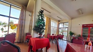 A dining area with red tables and chairs, a Christmas tree, and large windows. - Hotel Citymax Nakuru (Nakuru)