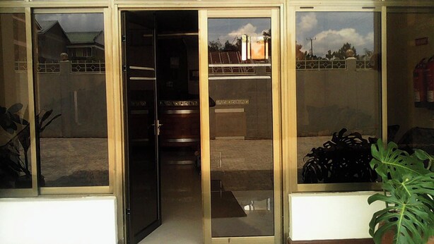 A reception area with a glass door, a view of the outside, and a potted plant on the right. - Hotel Citymax Nakuru (Nakuru)