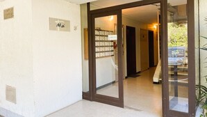 A hotel entrance with a sign reading "Mai" and a glass door leading to a hallway with multiple doors.