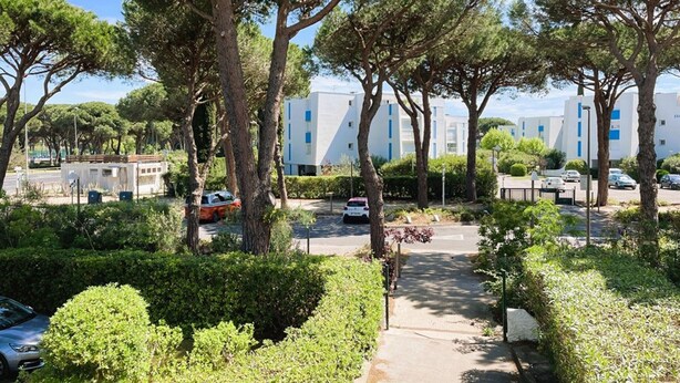 A residential area with modern buildings, a paved pathway, and parked cars.