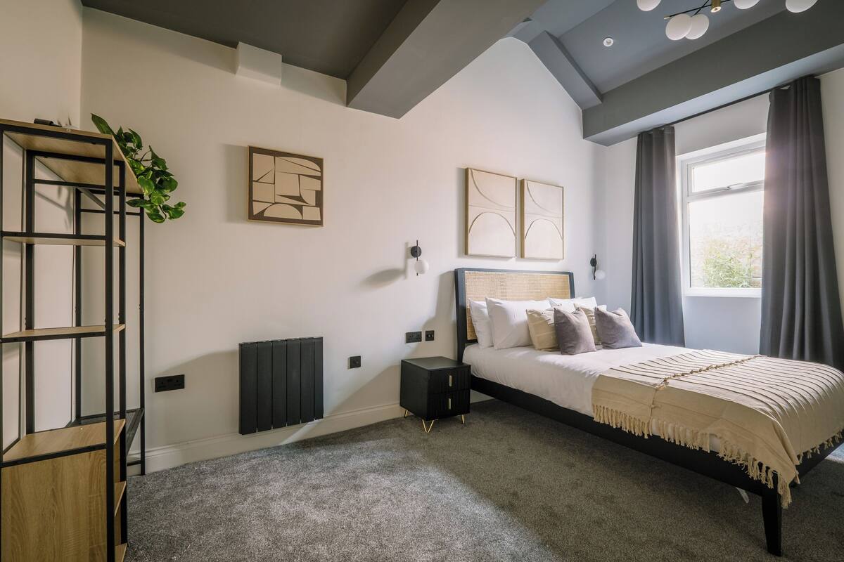 A bedroom with a bed, a nightstand, a radiator, and artwork on the walls.