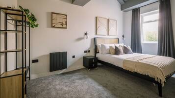A bedroom with a bed, a nightstand, a radiator, and artwork on the walls.