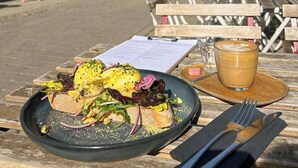 A meal at an outdoor table with a menu, a drink, and a view of a city street with shops and pedestrians. - Domain Boutique Rooms (Lancaster)