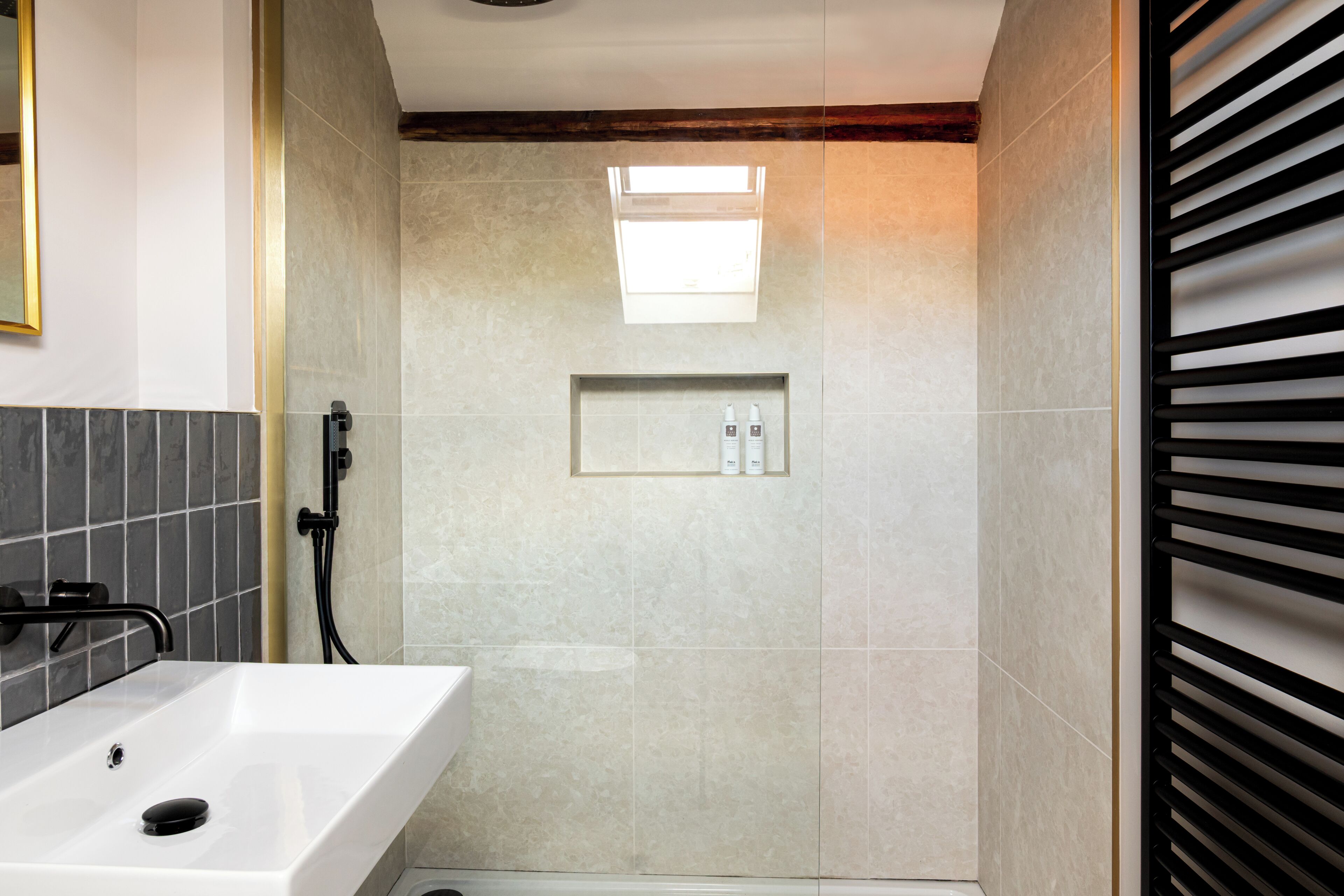 A bathroom with a white sink, a shower area, and a small shelf with toiletries.