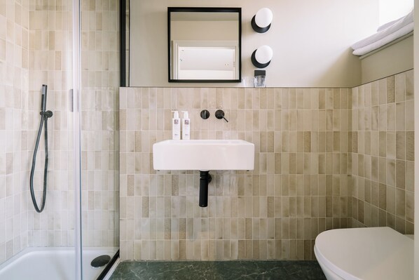 A bathroom with a shower, sink, and toilet. - Domain Boutique Rooms (Lancaster)