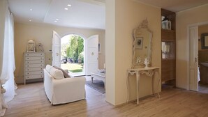 A spacious room with a white sofa, a wooden floor, a large mirror, and a door leading to a bathroom. - Villa Forte dei Marmi Pool & Garden (Forte dei Marmi)