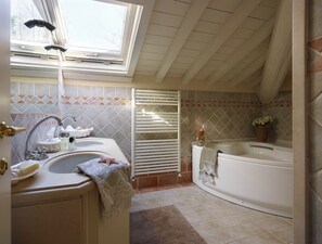 Un baño con tragaluz, una bañera y un lavamanos con artículos de aseo.