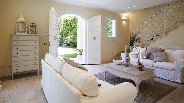 A spacious living room with a white sofa, a coffee table, and a staircase leading to a balcony. - Villa Forte dei Marmi Pool & Garden (Forte dei Marmi)