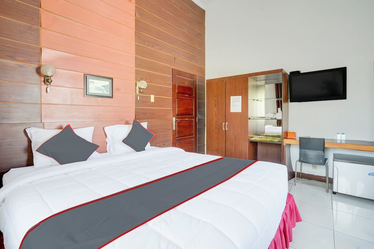 Une chambre d’hôtel dotée d’un grand lit, de murs recouverts de panneaux de bois, d’un bureau avec une chaise, d’un téléviseur à écran plat et d’un minibar.