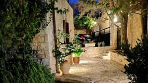 A stone staircase leading up to a building entrance, surrounded by greenery and potted plants. - Electra Stone Suite  (Roumeli)