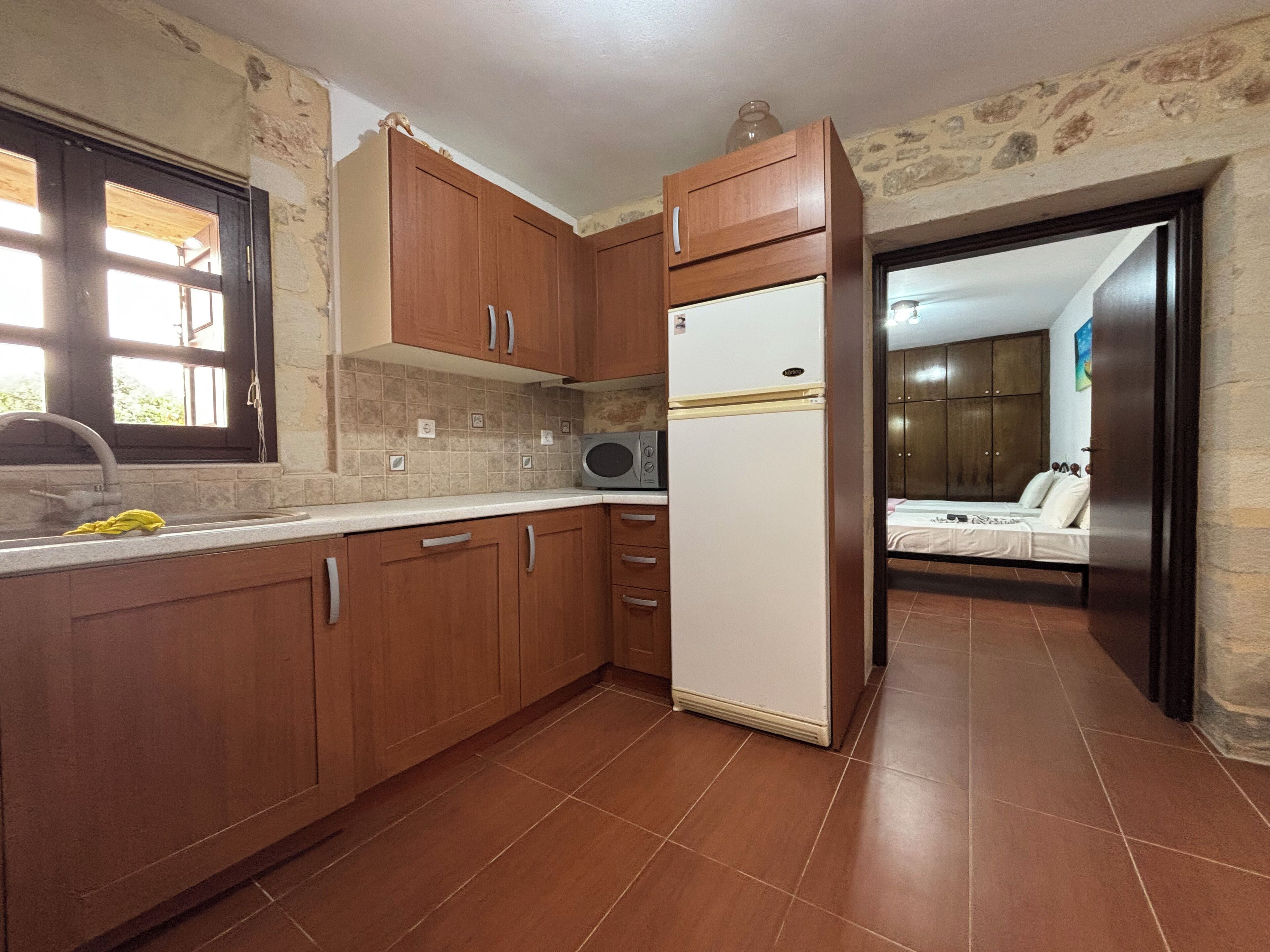 Una cocina con armarios de madera, un refrigerador blanco y una ventana con vistas al exterior.