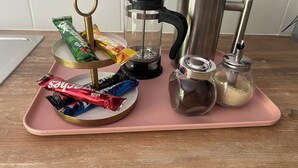 A pink tray with a coffee maker, a glass jar, a sugar container, and some chocolate bars. - ALBARINE la Source river/lakes, waterfalls and mountains, plastics processing business (Arbent)