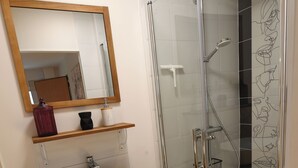 A modern bathroom with a glass shower enclosure, a wooden vanity with a sink, and a black and white checkered floor. - ALBARINE la Source river/lakes, waterfalls and mountains, plastics processing business (Arbent)