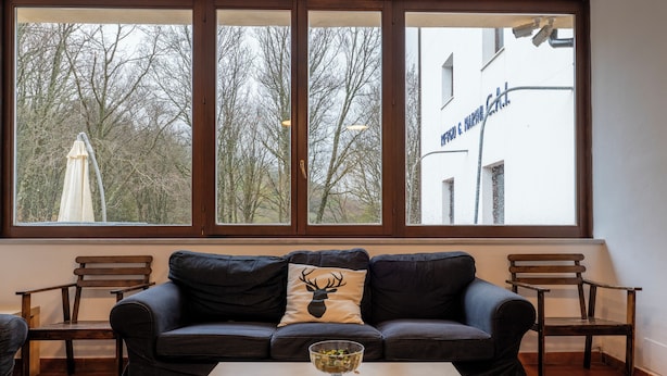 A living room with a large window, a sofa, a coffee table, and a chair. - Rifugio Giuliano Marini (Petralia Sottana)