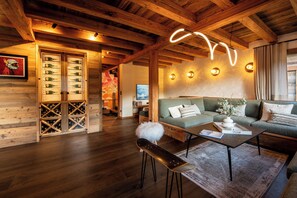 Um interior acolhedor em madeira, com um sofá, uma mesa de centro e um espaço para vinhos.