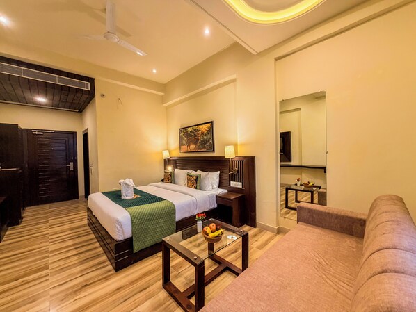 A hotel room with a bed, a glass coffee table, a sofa, a TV, and a mirror. - Spree Resort Jim Corbett (Ramnagar)
