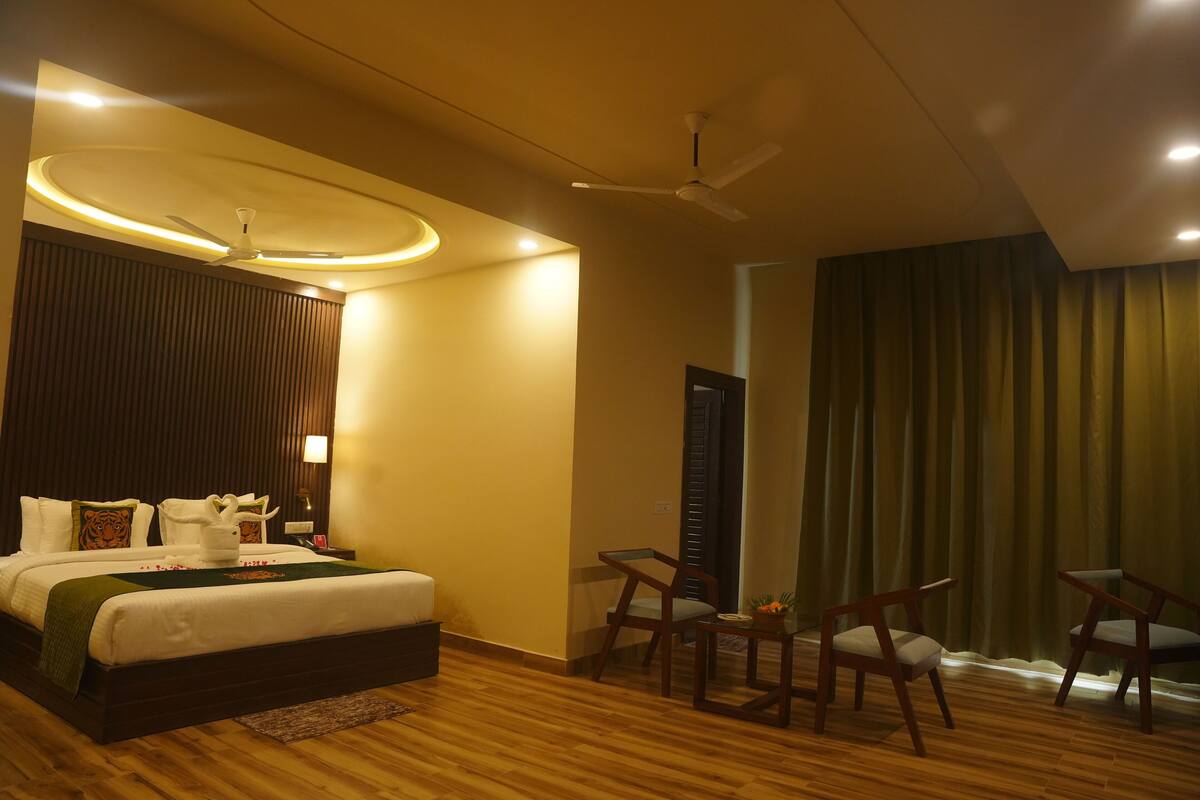 A modern hotel room with a large bed, a ceiling fan, and a seating area with two chairs.