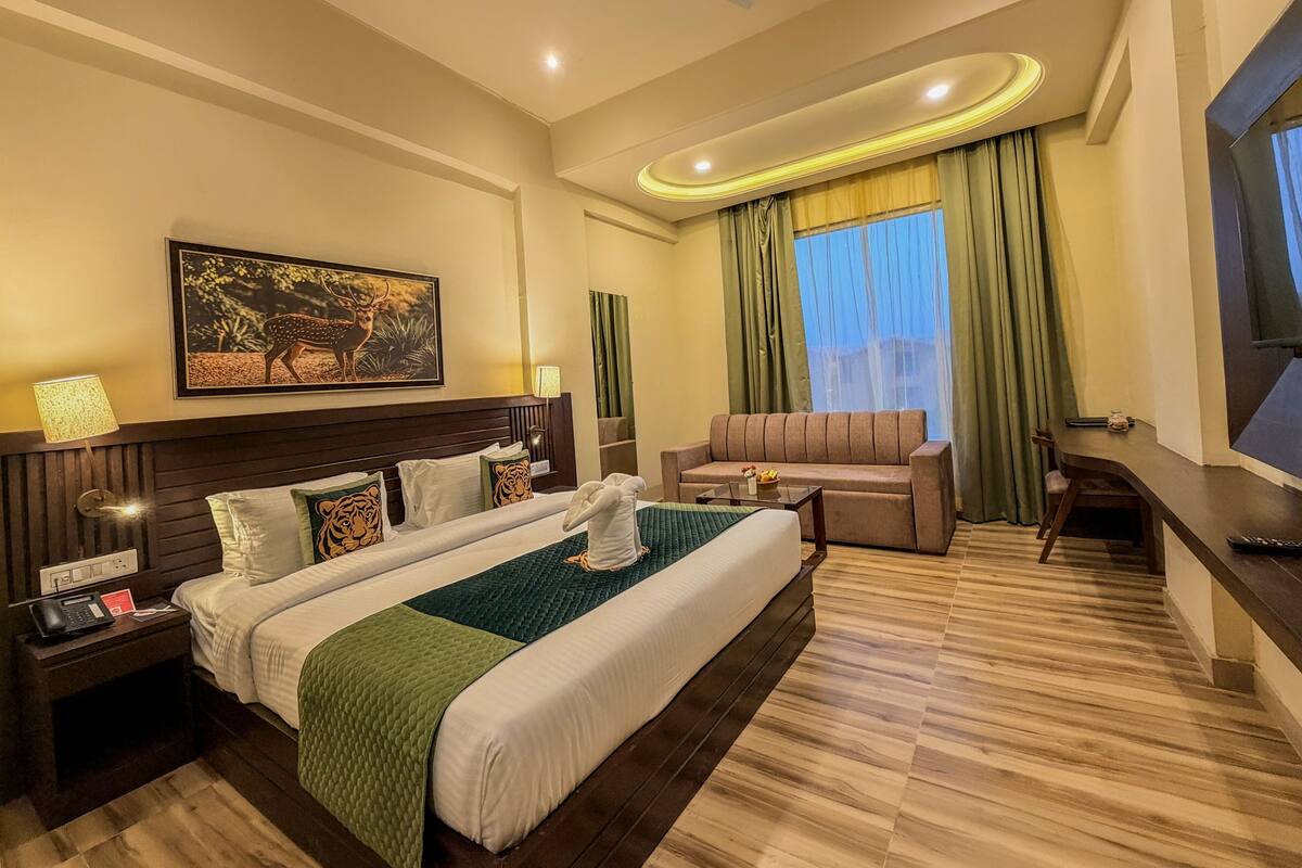 A hotel room with a large bed, a sofa, a TV, and a desk.