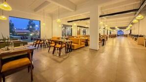 Un espaiós restaurant amb sostres alts, il·luminació penjant i vistes cap a l'exterior.