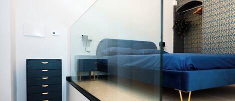 Un dormitorio con cama, cómoda y mampara de vidrio.