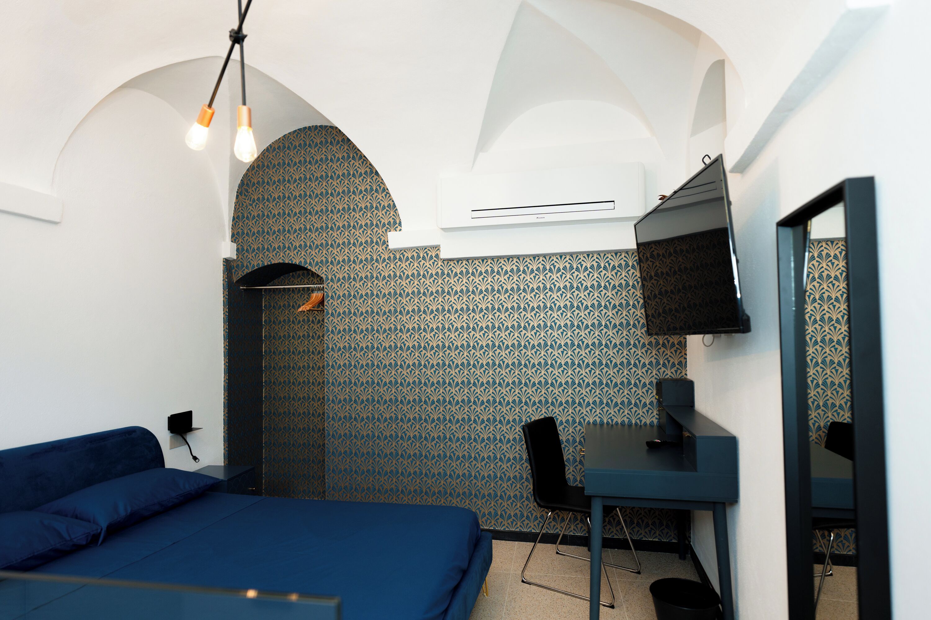 Ein Schlafzimmer mit Bett, Schreibtisch, Stuhl und Fernseher.