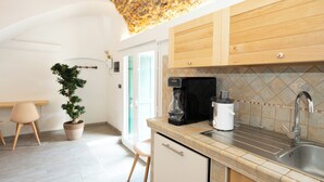 A modern kitchen with a stone ceiling, wooden cabinets, a coffee maker, and a sink. - SECRET SUITE VARIGOTTI (Varigotti)