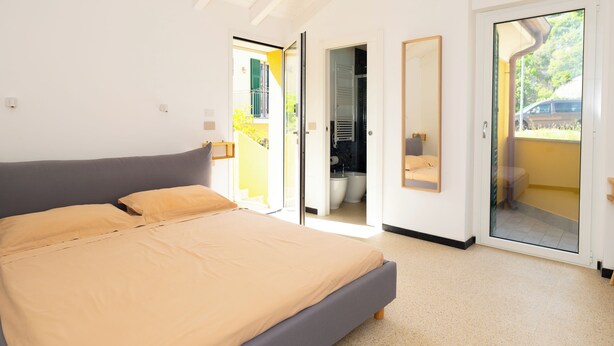A bedroom with a bed, a bathroom, and a sliding glass door leading to a balcony. - SECRET SUITE VARIGOTTI (Varigotti)