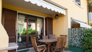 Une terrasse avec une table et des chaises en bois, un petit coin cuisine extérieur et un espace salon abrité.