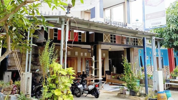 A small, open-air shop with a motorcycle parked outside, surrounded by various plants and gardening supplies. - Lishafa Homestay (Karimun Jawa)