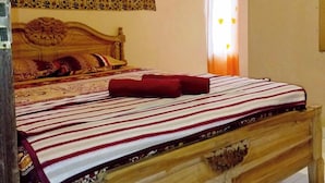 A wooden bed with a striped bedspread and red pillows, a floral-patterned headboard, and a window with curtains. - Lishafa Homestay (Karimun Jawa)