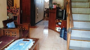 A living room with a sofa, a coffee table, a television, and a staircase. - Lishafa Homestay (Karimun Jawa)