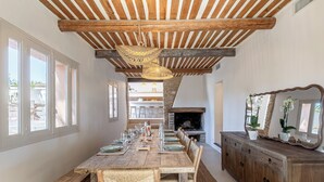 A dining area with a long wooden table set for six, flanked by wicker chairs, a wooden bench, and a wooden cabinet with a mirror. - Maison Paula - In the heart of the village & heated pool (Oppède)