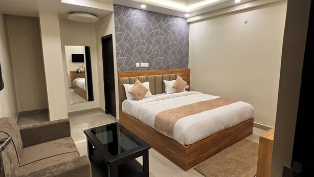 A modern bedroom with a large bed, a sofa, a glass coffee table, and a ceiling fan. - Hotel Paradise Premier (Danapur)