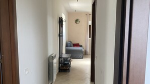 A narrow hallway with a radiator, a coat rack, and a small table with a chair. - Pezzelelle (Roccamorice)