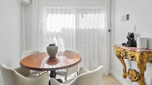 A dining area with a round wooden table, white chairs, a vase, and a decorative gold table with a vase and a black sculpture. - Gallery on Kent | Prime Location (Newtown)