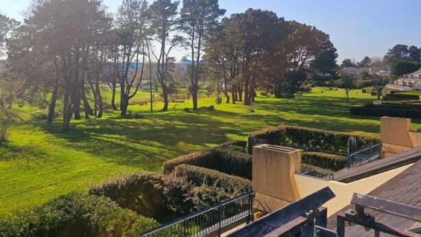 Un parc avec des haies soigneusement taillées, un mur de pierre et une vue dégagée sur les environs.