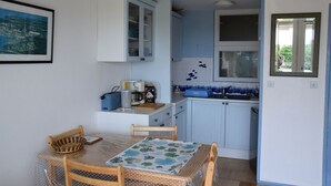 Une cuisine de taille réduite comprenant une table à manger, des chaises et un réfrigérateur.