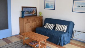 Un salon avec un canapé bleu, un meuble en bois et un tableau encadré accroché au mur.